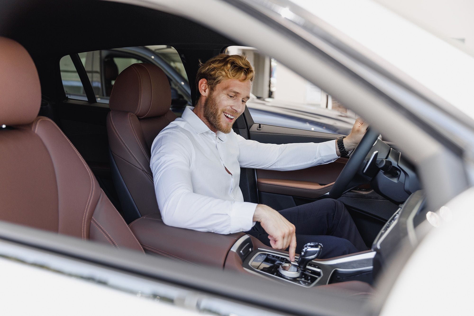 Man in white shirt sitting in car with brown interior